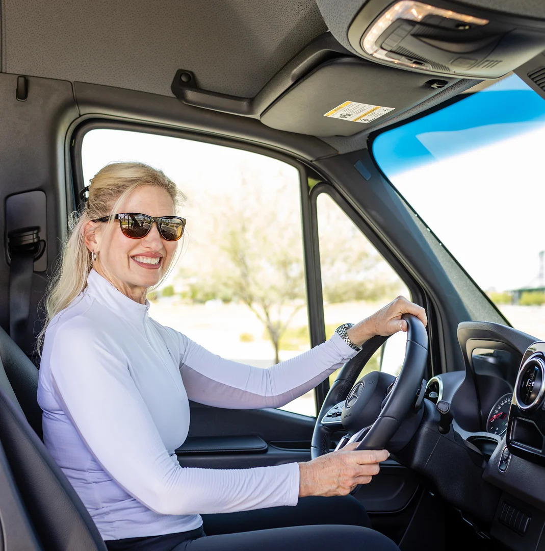Woman wearing sunglasses driving a car on a sunny day.